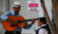 Un chanteur de rue joue de la guitare devant un local commercial à louer à Guayaquil, en Équateur, le 9 août 2025 ( AFP / MARCOS PIN )