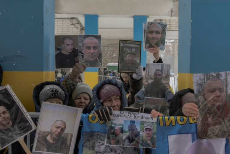 Des personnes tiennent des portraits de leurs proches et amis disparus ou capturés alors qu'elles attendent l'arrivée des prisonniers de guerre ukrainiens libérés dans la région de Tchernihiv, dans un lieu tenu secret, le 5 février 2026, dans le contexte de l'invasion russe de l'Ukraine. L'Ukraine et la Russie ont procédé à leur premier échange de prisonniers depuis des mois, libérant chacune au moins 157 personnes. ( AFP / Roman PILIPEY )