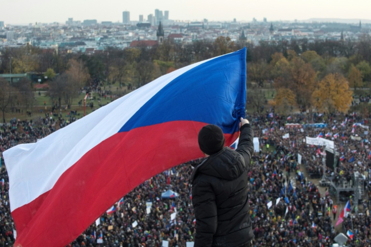 Un homme brandit un drapeau tchèque au-dessus d'une foule de manifestants lors d'un rassemblement contre le Premier ministre tchèque Andrej Babis, à la veille de l'anniversaire de la Révolution de velours, à Prague, le 16 novembre 2019 ( AFP / Michal Cizek )
