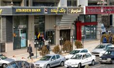 Des Iraniens passent devant une succursale de la banque Ayandeh (G) dans la capitale Téhéran, le 14 janvier 2017 ( AFP / ATTA KENARE )