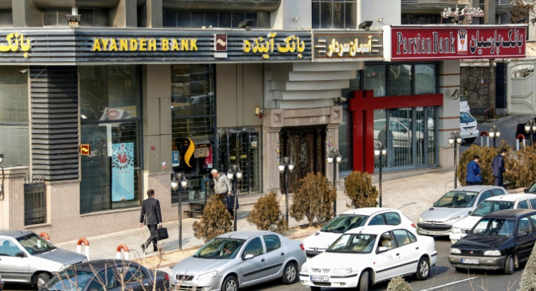Des Iraniens passent devant une succursale de la banque Ayandeh (G) dans la capitale Téhéran, le 14 janvier 2017 ( AFP / ATTA KENARE )