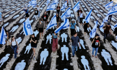 Des personnes brandissent des drapeaux israéliens alors qu'elles traversent une installation commémorative mise en place sur la plage de Tel-Aviv pour marquer le troisième anniversaire de l'attaque du Hamas contre Israël, le 7 octobre 2026 ( AFP / Jack GUEZ )