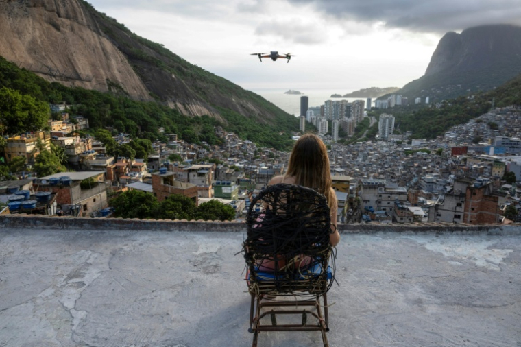Une touriste se fait filmer par un drone sur le toit d'une maison dans la favela de Rocinha, à Rio de Janeiro, au Brésil, le 5 mars 2026 ( AFP / Pablo PORCIUNCULA )