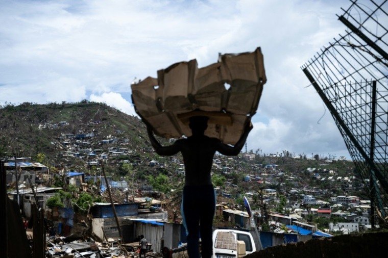 Un homme muni de tôles pour reconstruire sa maison dans le bidonville de Cavani, à Mamoudzou, à Mayotte, le 2 janvier 2025 ( AFP / JULIEN DE ROSA )