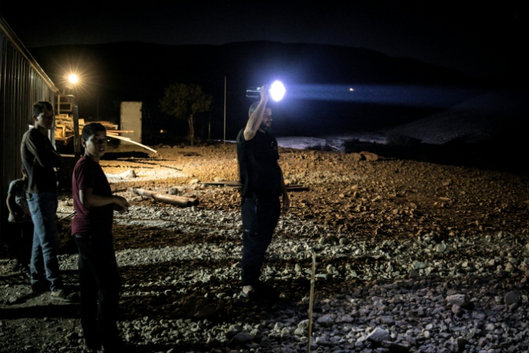 Des bédouins palestiniens s'éclairent d'une torche pour surveiller l'éventuelle survenue de colons israéliens à à Ras Ein al-Auja, dans la vallée du Jourdain, en Cisjordanie occupée, le 29 septembre 2025 ( AFP / JOHN WESSELS )