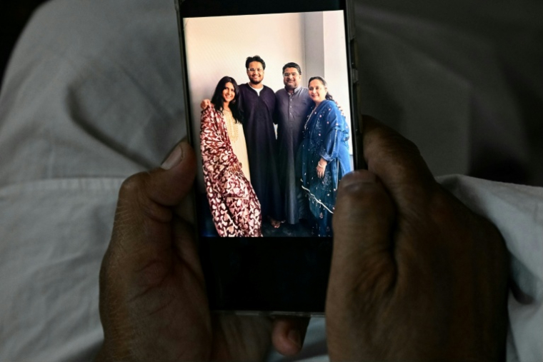 Badasab Saiyed, universitaire à la retraite, qui a perdu son frère, sa belle-sœur, son neveu et sa nièce dans le crash du vol 171 d'Air India, montre leur photo lors d'un entretien avec l'AFP à son domicile à Ahmedabad, le 11 novembre 2025 en Inde ( AFP / Indranil MUKHERJEE )