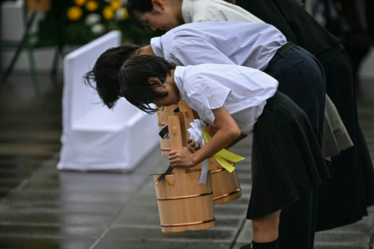 Des élèves réalisent un rituel avec des seaux d'eau comme offrandes, le 9 août 2025 à Nagasaki pour marquer les 80 ans du bombardement atomique de la ville ( AFP / Philip FONG )