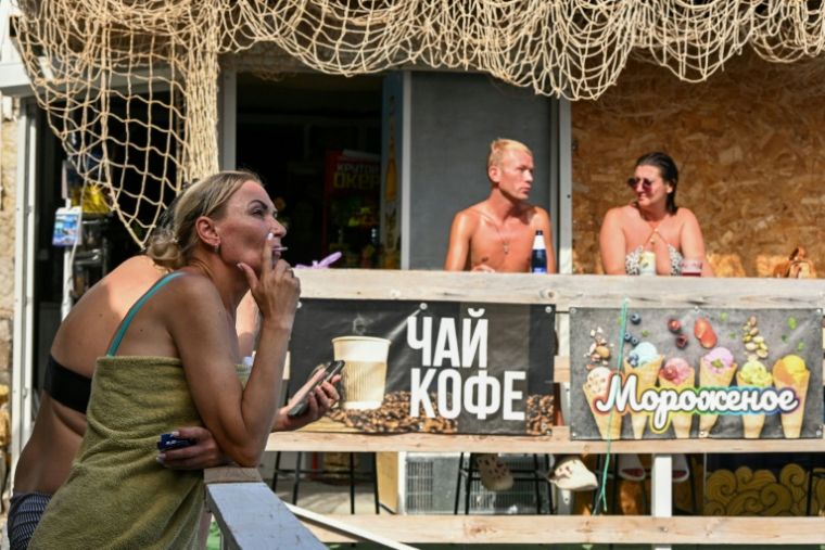 Sur une plage à Simeïz, en Crimée annexée, des touristes attablés à un café, le 21 juillet 2026 ( AFP / Igor IVANKO )