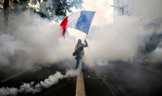 Un manifestant agite un drapeau français au milieu des gaz lacrymogènes lors d'une nouvelle manifestation contre la vie chère, le 31 octobre 2026 à Lyon ( AFP / JEFF PACHOUD )