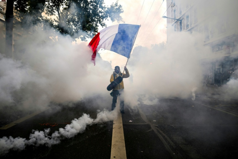 Un manifestant agite un drapeau français au milieu des gaz lacrymogènes lors d'une nouvelle manifestation contre la vie chère, le 31 octobre 2026 à Lyon ( AFP / JEFF PACHOUD )