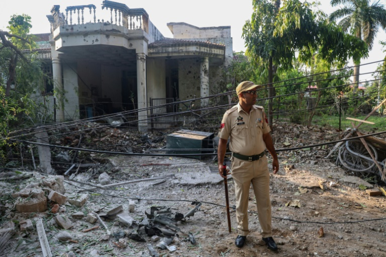 Un policier indien devant une maison endommagée par des tirs d'artillerie pakistanais, le 10 mai 2025 à Jammu, au Cachemire indien ( AFP / Rakesh BAKSHI )