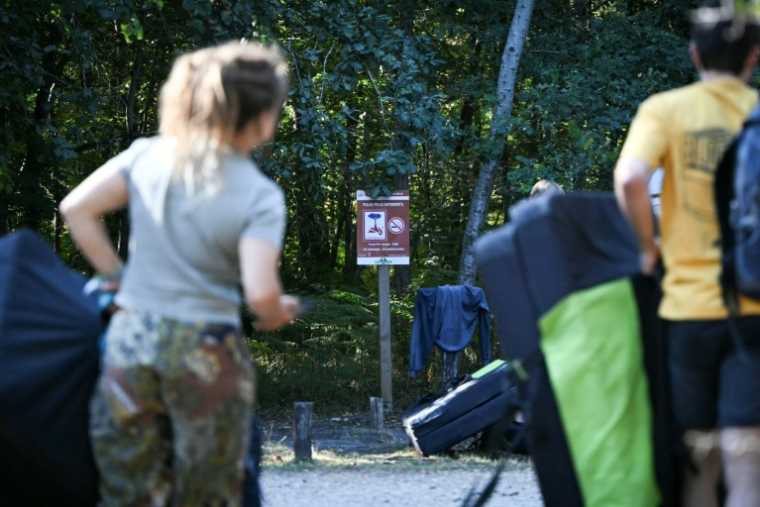 Des visiteurs devant un panneau "Tous feux interdits" au premier jour de la réouverture au public de la forêt de Fontainebleau partiellement dévastée par les flammes en juillet, le 22 août 2026 près de Arbonne-la-forêt, en Seine-et-Marne  ( AFP / Lou BENOIST )