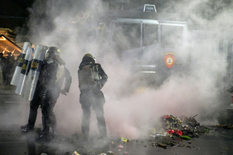 Des policiers anti-émeutes éteignent un incendie lors d'une manifestation contre la hausse du prix des carburants non subventionné et le programme phare de repas gratuits du président Prabowo, le 26 juin 2026 à Surabaya, en Indonésie ( AFP / Juni KRISWANTO )