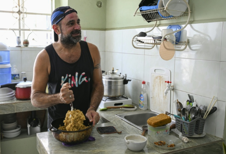Roberto Ronda cuisine à son domicile pour le petit commerce de repas qu'il a lancé, le 31 juillet 2026 à La Havane  ( AFP / YAMIL LAGE )