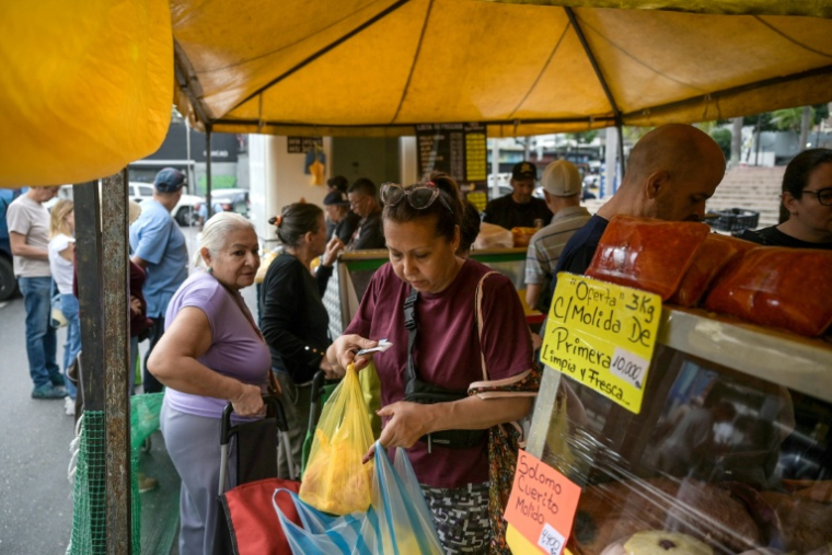 Des personnes font leurs courses sur un marché de rue à Caracas, le 20 décembre 2025 au Venezuela ( AFP / Juan BARRETO )