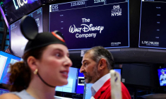 Un écran affiche le logo et les informations boursières de The Walt Disney Company tandis que des traders travaillent sur le parquet de la Bourse de New York (NYSE) à New York