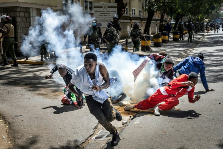 Des manifestants courent se mettre à l'abri d'une grenade lacrymogène lancée par la police lors d'un rassemblement contre la mort du blogueur kenyan Albert Ojwang, le 12 juin 2025 à Nairobi ( AFP / Luis TATO )