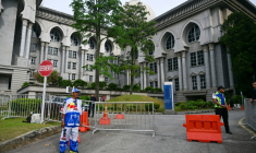 Un partisan de l'ex-Premier ministre malaisien Najib Razak (à gauche), habillé aux couleurs de son parti, se tient devant le palais de justice de Putrajaya, en Malaisie, le 26 décembre 2025 ( AFP / Mohd RASFAN )