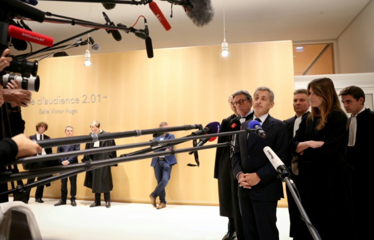 L'ancien président Nicolas Sarkozy (4e. à g.) devant la presse à la sortie de la salle d'audience au tribunal de Paris, le 25 septembre 2025 ( AFP / Alain JOCARD )