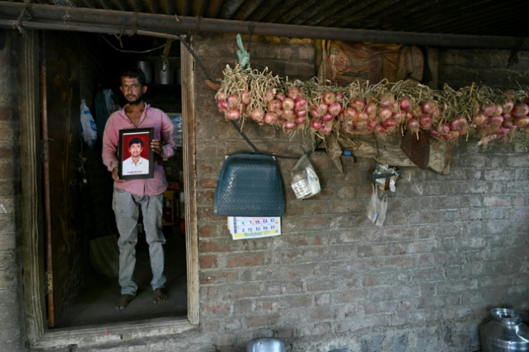 L'agriculteur Balaji Khindkar montre une photo de son frère d'Amol, qui s'est suicidé en raison de l'accumulation de prêts financiers, devant sa maison du village d'Ambilwadgaon, dans l'Etat du Maharashtra, le 3 mai 2025 en Inde ( AFP / Indranil MUKHERJEE )