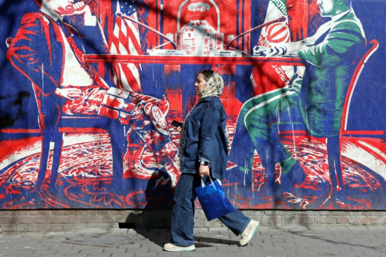 Une Iranienne passe devant un panneau anti-américain représentant des discussions Entre les deux pays, à Téhéran, le 26 février 2026 ( AFP / - )