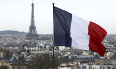 Un drapeau français flotte au-dessus de la ligne d'horizon, avec la Tour Eiffel en arrière-plan, à Paris