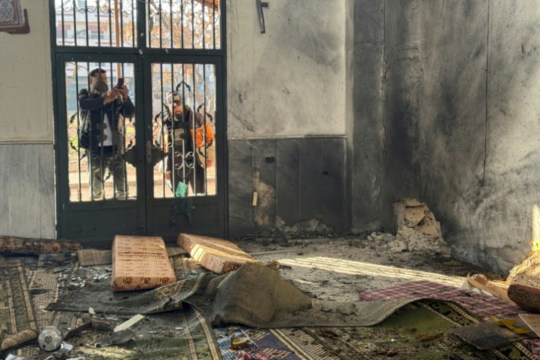 Un homme prend une photo des dégâts causés par l'explosion à l'intérieur de la mosquée Ali Ben Abi Taleb, dans le quartier de Wadi al-Dahab à Homs, le 26 décembre 2025 ( AFP / Omar HAJ KADOUR )