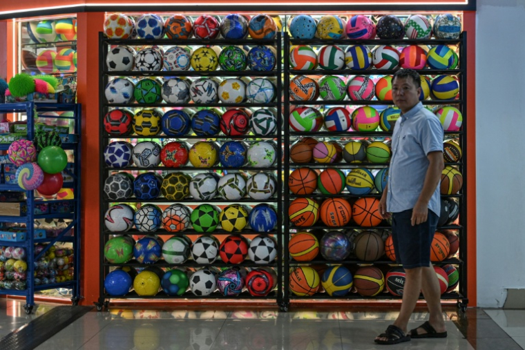 Un homme passe devant un stand d'articles de sport vendant des ballons au marché international de Yiwu, dans la province du Zhejiang, dans l'est de la Chine, le 17 septembre 2025 ( AFP / Jade GAO )