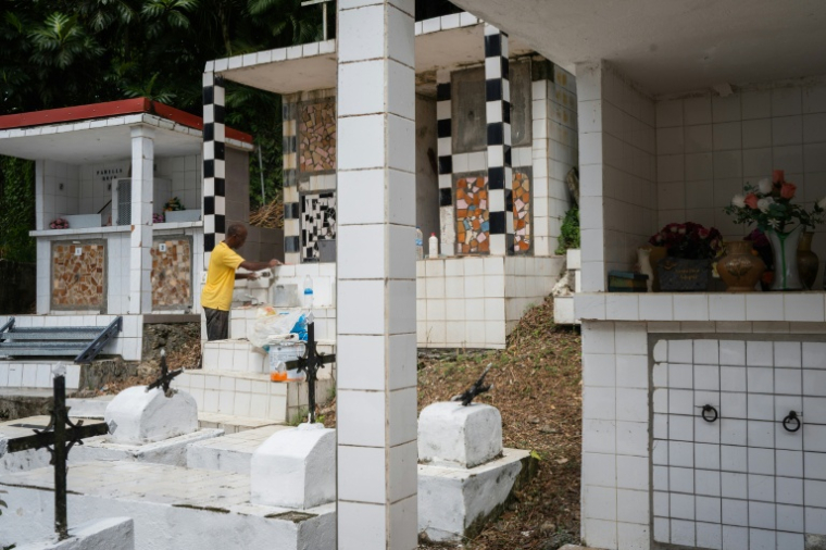 Un membre de la famille Vainqueur décore une tombe dans le cimetière privé de la famille aux  Abymes, en Guadeloupe, le 31 octobre 2025 ( AFP / Carla Bernhardt )