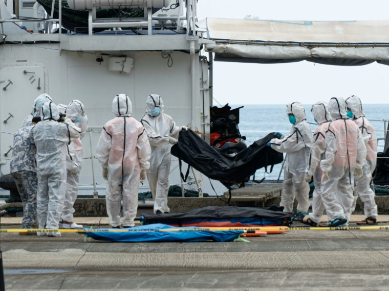 Des membres des garde-côtes philippins déchargent des sacs mortuaires contenant les victimes de l'incendie d'un ferry au port de Borac, à Coron, aux Philippines, le 12 septembre 2026 ( AFP / Ron Lopez )