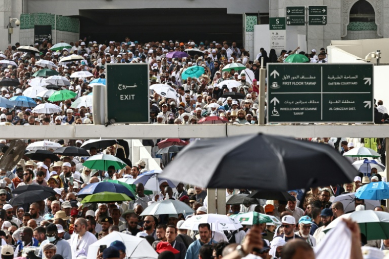 Des fidèles musulmans déambulent dans le complexe de la Grande Mosquée sous les brumisateurs installés dans la ville sainte de La Mecque, le 24 mai 2026  en Arabie saoudite, à la veille du pèlerinage annuel du Hajj ( AFP / Zain JAAFAR )