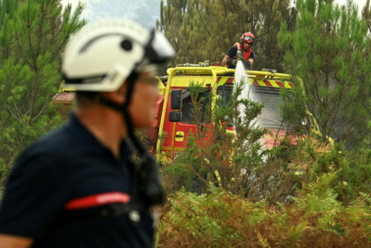 Des pompiers arrosent de la végétation pour éviter une reprise de feu près de Luglon, dans les Landes, le 15 août 2026 ( AFP / Gaizka IROZ )
