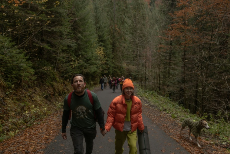 Anastassia Podobaïlo (d) et son collègue et époux Mykola Iassinenko participent à une randonnée lors d'une retraite en montagne destinée à soutenir le rétablissement psychologique et le bien-être mental des médecins militaires ukrainiens dans la région de Transcarpatie, dans l'ouest de l'Ukraine, le 27 octobre 2025 ( AFP / Roman PILIPEY )