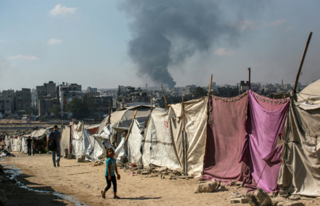 Des Palestiniens devant des tentes à Gaza-ville avec en arrière-plan une colonne de fumée s'élevant du centre de la bande de Gaza après un bombardement israélien, le 6 juillet 2025 ( AFP / Bashar TALEB )
