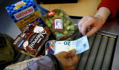 Une femme paie avec un billet de vingt euros à la caisse d'un supermarché