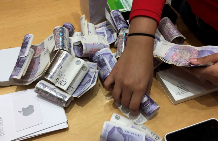 Un vendeur compte des piles de billets de livres sterling