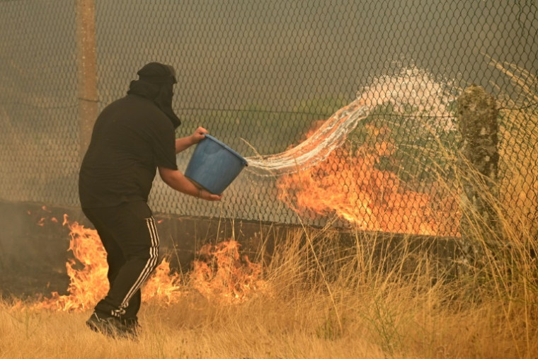 Un habitant tente de lutter contre un incendie de forêt avec un seau, dans le village de Santa Baia de Montes, province d'Ourense, dans le nord-ouest de l'Espagne, le 14 août 2025 ( AFP / MIGUEL RIOPA )