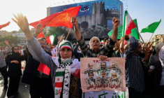 Des Iraniens brandissent des drapeaux et des pancartes lors d'un rassemblement de protestation contre l'attaque américaine en Iran sur la place Enghelab à Téhéran, le 22 juin 2025 ( AFP / ATTA KENARE )