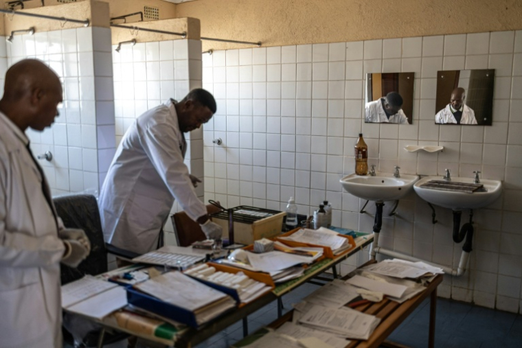 Le microscopiste Amrstrong Mgiba (G) attend que son collègue Nicholas Skhumbane (C) prépare des lames de sang avant de les examiner à la clinique Cunningmore de Bushbuckridge (Afrique du Sud), le 26 mai 2026 ( AFP / EMMANUEL CROSET )