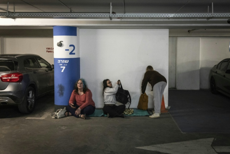 Des gens se mettent à l'abri dans un parking après que l'armée israélienne a annoncé avoir détecté des tirs de missiles d'Iran en direction d'Israël, le 28 février 2026  ( AFP / John WESSELS )