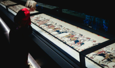Une femme se penche pour observer la Tapisserie de Bayeux lors d'une avant-première réservée à la presse, organisée en amont de l'inauguration officielle au British Museum, dans le centre de Londres, le 7 septembre 2026 ( AFP / Adrian DENNIS )