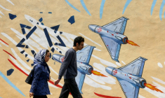 Un couple passe devant une peinture murale anti-américaine et anti-israélienne, à Téhéran, le 21 avril 2026 ( AFP / ATTA KENARE )
