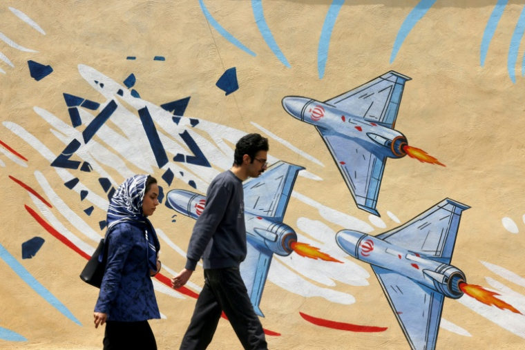 Des Iraniens passent à côté d'une fresque murale à Téhéran le 21 avril 2026. ( AFP / ATTA KENARE )