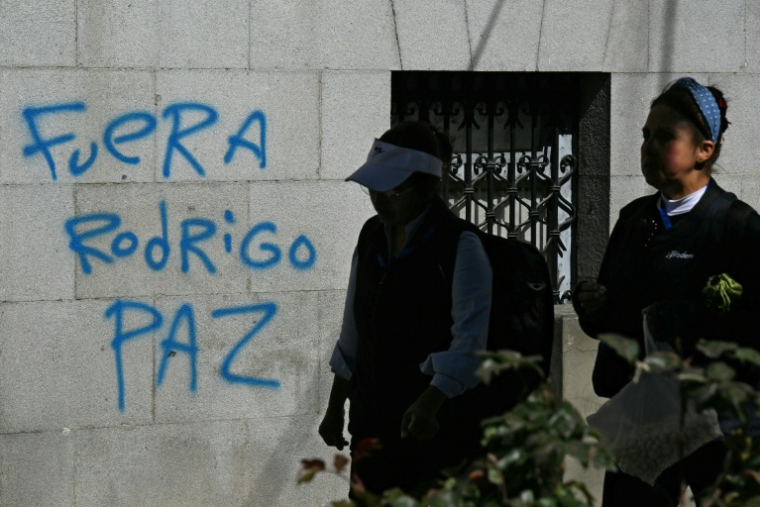 Des femmes passent devant un graffiti avec le slogan "Dehors Rodrigo Paz", en référence au président bolivien, à La Paz, le 19 mai 2026, en Bolivie ( AFP / AIZAR RALDES )
