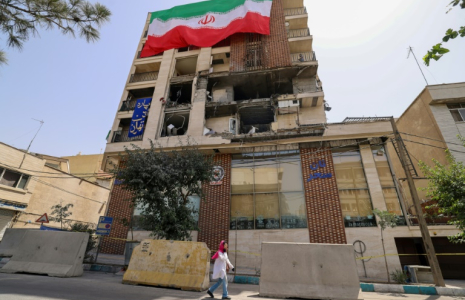 Un immeuble détruit par une frappe israélienne recouvert du drapeau iranien, à Téhéran le 25 juin 2025 ( AFP / ATTA KENARE )