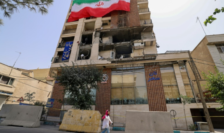 Un immeuble détruit par une frappe israélienne recouvert du drapeau iranien, à Téhéran le 25 juin 2025 ( AFP / ATTA KENARE )