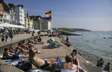 La plage de Wimereux le 18 juin 2025, avec ses baigneurs et sa gare voisine où s'abritent quelques migrants en quête d'ombre ( AFP / Sameer Al-DOUMY )