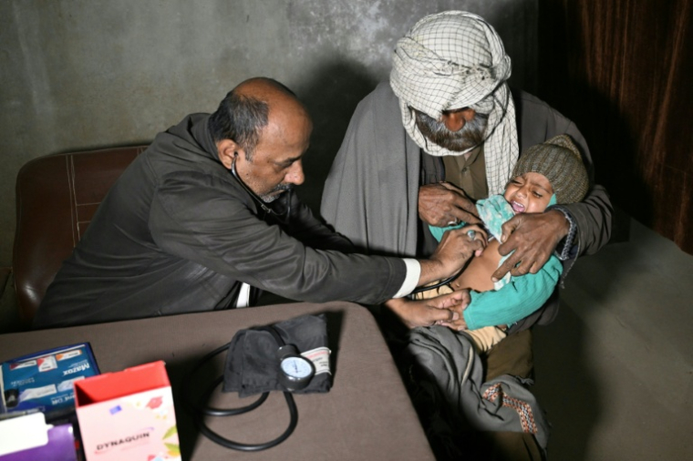 Abdul Waheed (g) examine un enfant dans sa clinique non agréée située à la périphérie de la ville d'Hyderabad, dans la province du Sind, le 8 janvier 2026 au Pakistan ( AFP / Rizwan TABASSUM )