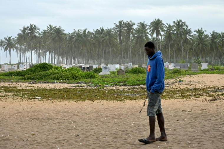 Un homme marche devant le nouveau cimetière de Lahou-Kpanda (Côte d'Ivoire), après la destruction de l'ancien par l'érosion dans ce village situé à 140 km d'Abidjan, le 3 août 2025 ( AFP / Issouf SANOGO )