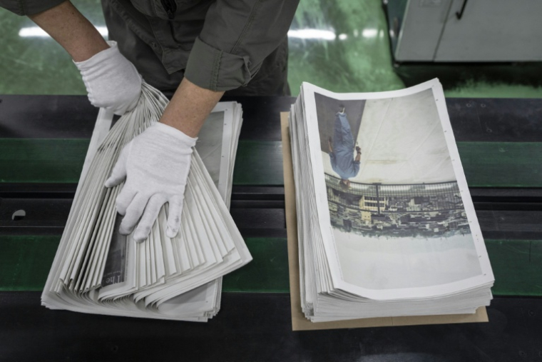 Un employé emballe l'œuvre du photographe Kazuma Obara, "The Newspaper", à Kumiyama, au Japon, le 19 mars 2026 ( AFP / Yuichi YAMAZAKI )